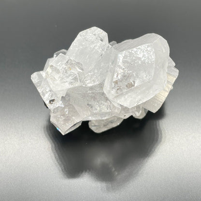 White Apophyllite Clusters – 20–30 MM natural white crystal cluster specimen with clear, reflective points on dark background
