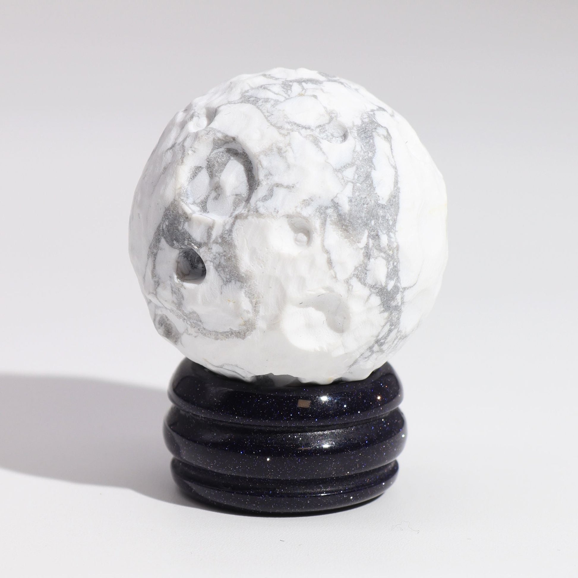 Alt Tag: White Howlite Gemstone Planet – 40MM Solar Goldstone Stand, white howlite sphere with gray veining on dark sparkling stand