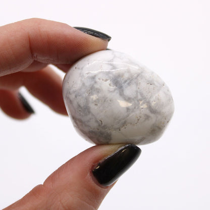 Alt Tag: White Howlite Magnesite Tumble Stones – Bag of 6, polished white and gray tumble stone held between fingers close-up
