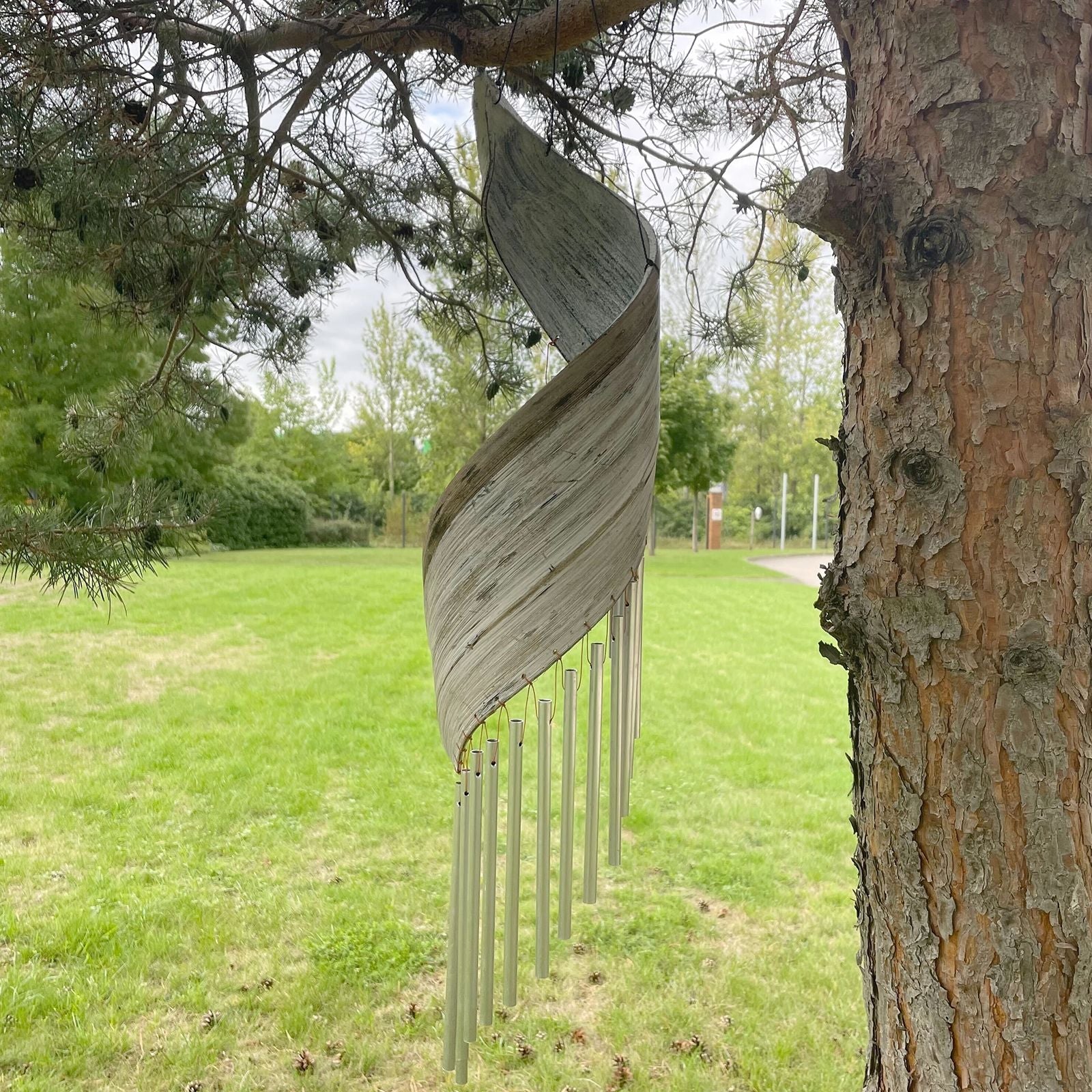 Whitewashed Coconut Leaf Wind Chimes – 50x13 CM colgando de un árbol en jardín, hojas de coco blanqueadas y tubos metálicos