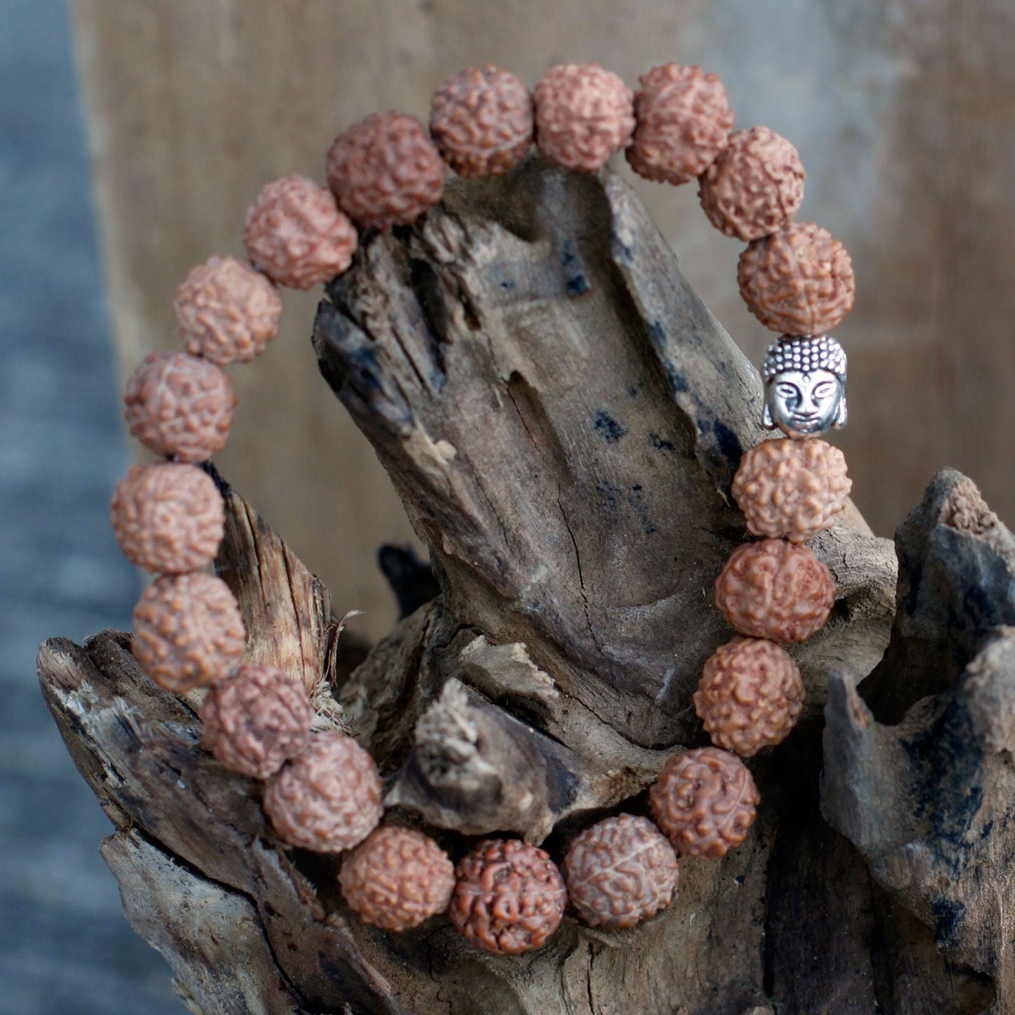Alt Tag: Wood Bead Buddha Bangle Mala – Brown with Rudraksha-style beads and Buddha charm bracelet on rustic wood