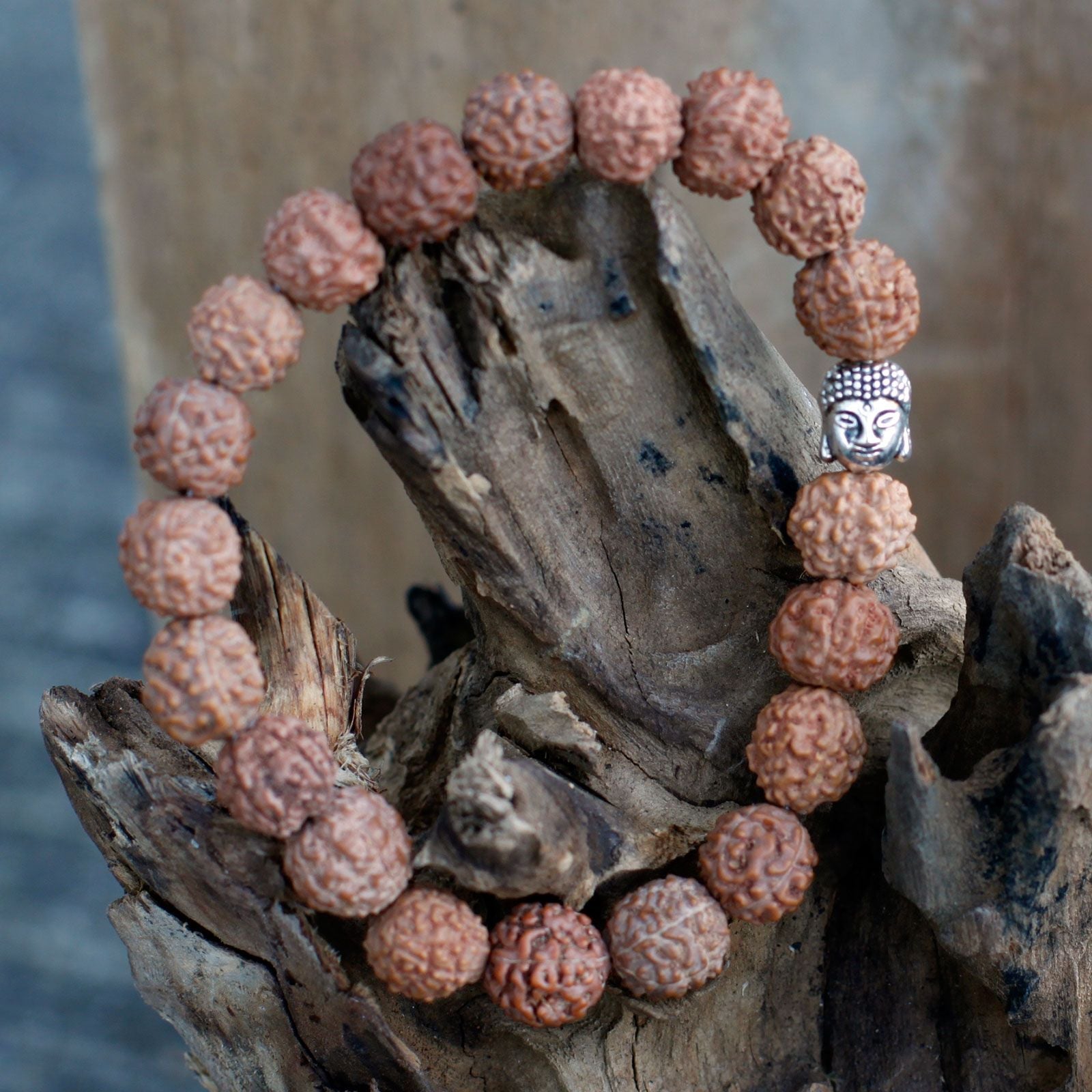 Alt Tag: Wood Bead Buddha Bangle Mala – Brown with Rudraksha-style beads and Buddha charm bracelet on rustic wood