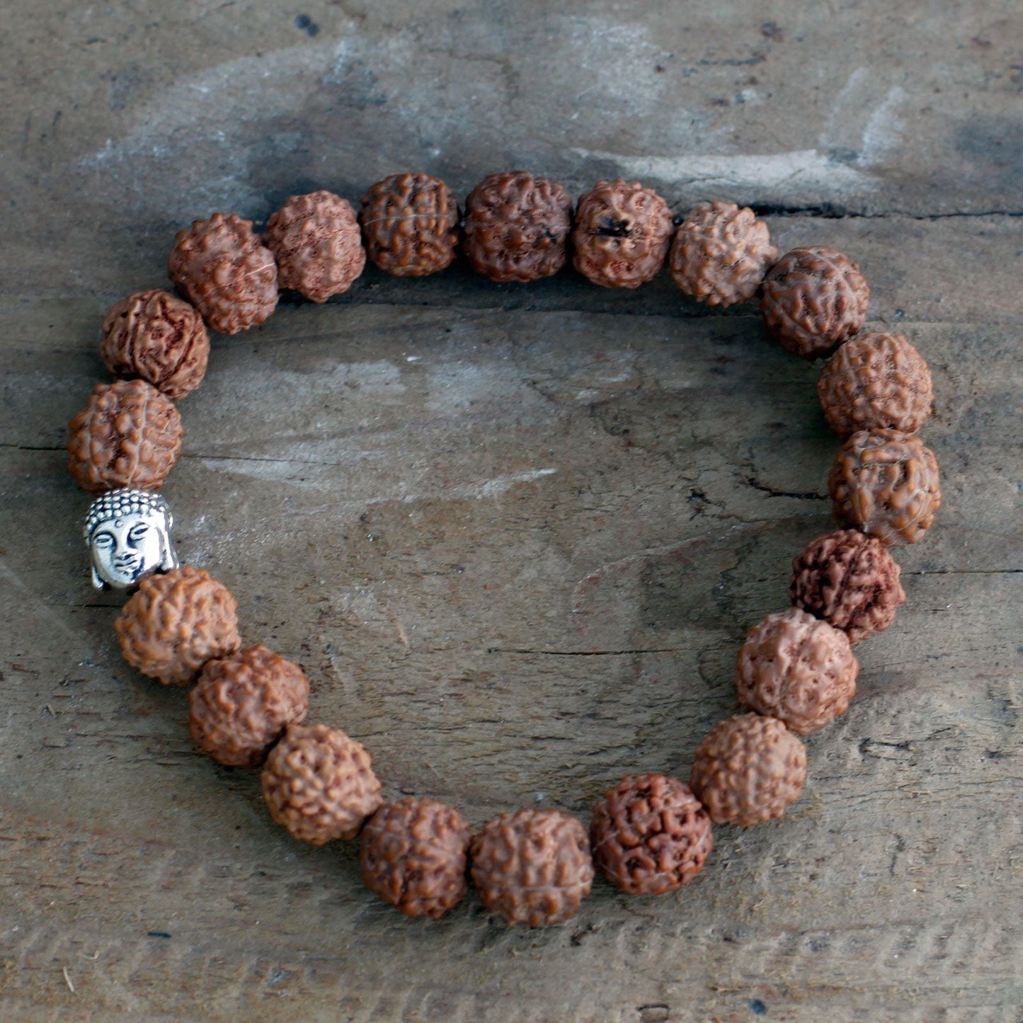 Alt Tag: Wood Bead Buddha Bangle Mala – Brown bracelet with Rudraksha-style wood beads and silver Buddha charm on rustic wooden background
