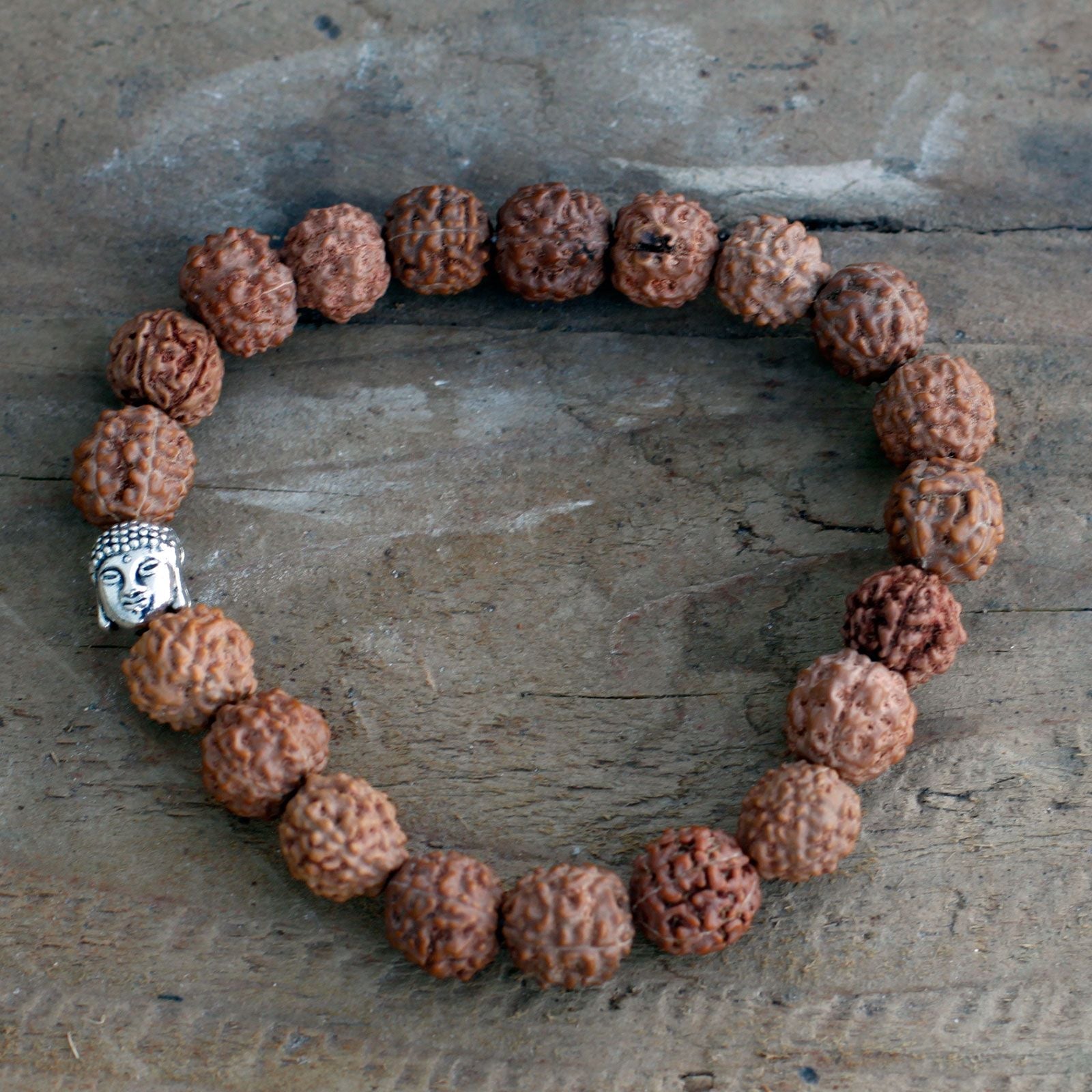 Alt Tag: Wood Bead Buddha Bangle Mala – Brown bracelet with Rudraksha-style wood beads and silver Buddha charm on rustic wooden background