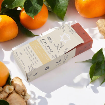 Alt Tag: Yellow Clay Exfoliating Soap – 145G barra de jabón con arcilla amarilla y posos de café, con naranjas y jengibre en fondo blanco