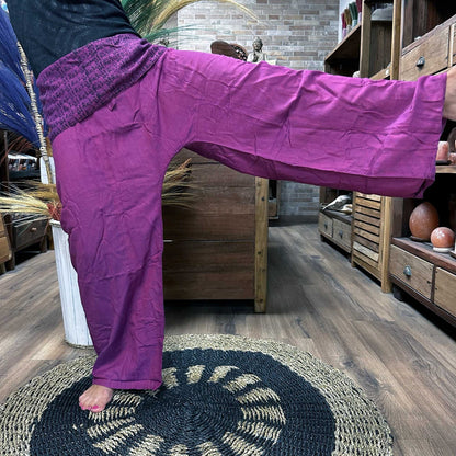 Yoga- och festivalbyxor – Thai Fisherman Mandala Mantra på lila, lila Thai fisherman-byxor i 100% bomull som bärs i en sidolyft-position med benet