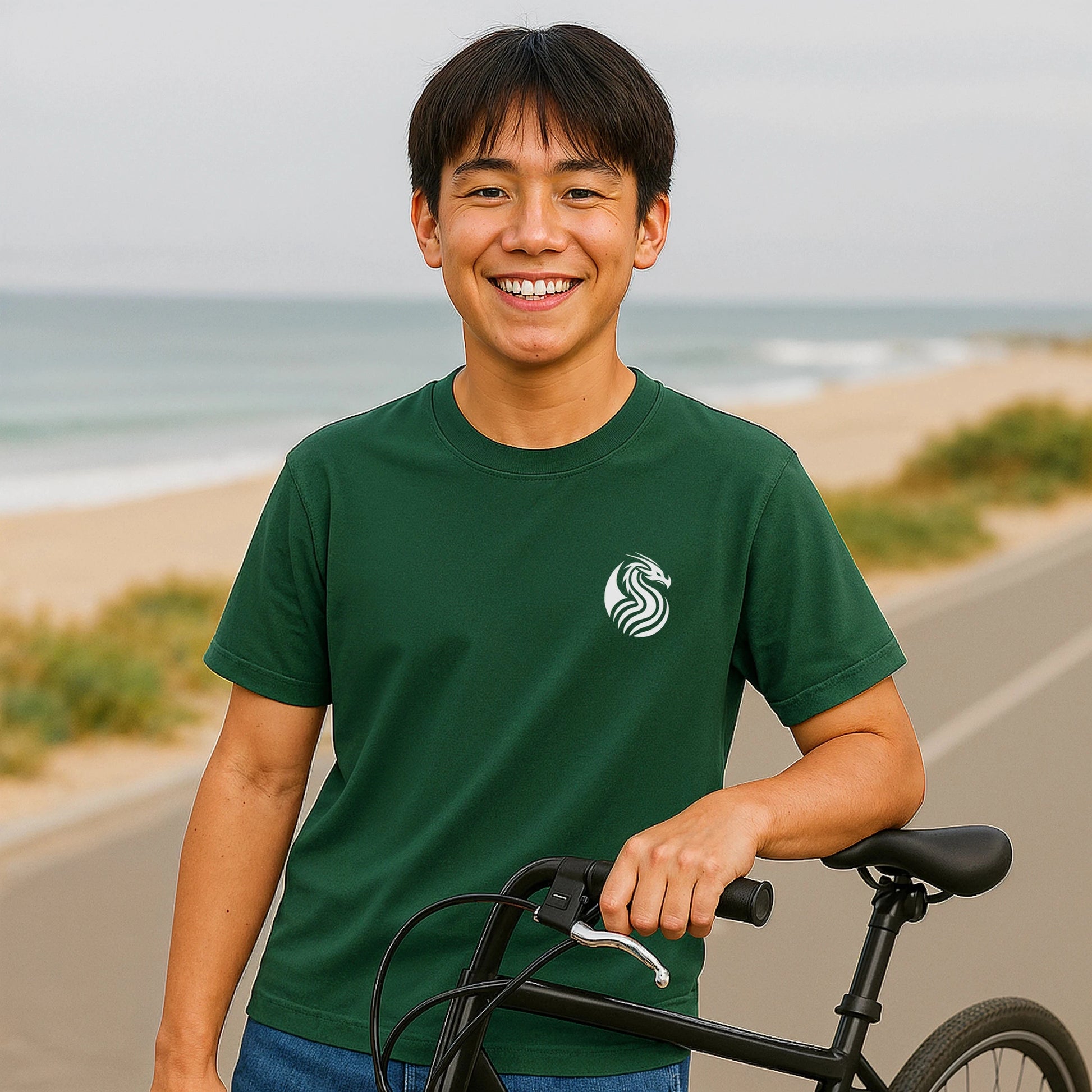 Alt Tag: Young Dragon Premium Unisex T-Shirt in green with dragon logo, worn by model holding bicycle near beach road